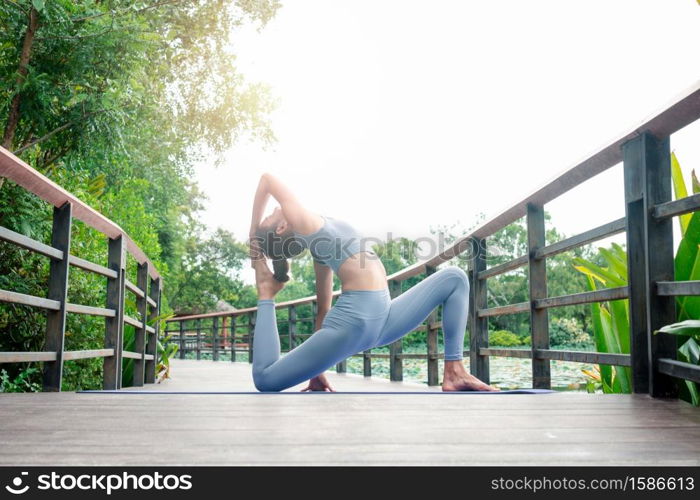 Portrait of a young woman doing yoga in the garden for a workout. Concept of lifestyle fitness and healthy. Asian women are practicing yoga in the park.