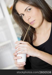 Portrait of a young woman drinking a cold drink with a drinking straw