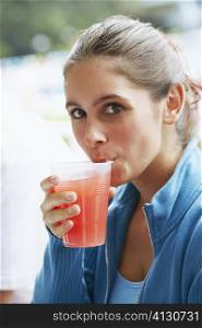 Portrait of a young woman drinking a glass of juice