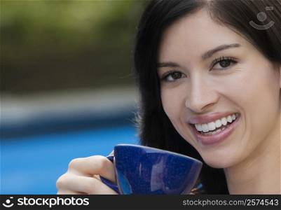 Portrait of a young woman drinking tea and smiling