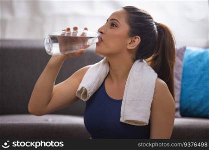 Portrait of a young woman drinking water from a bott≤during workout