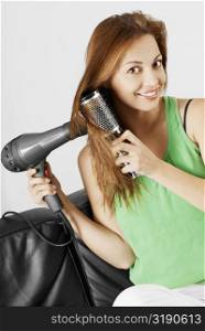 Portrait of a young woman drying her hair with a hair dryer