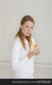 Portrait of a young woman eating a banana