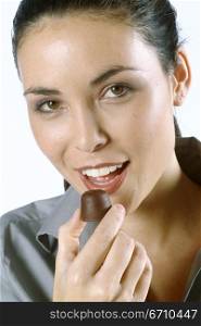 Portrait of a young woman eating a chocolate