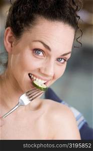 Portrait of a young woman eating a cucumber slice