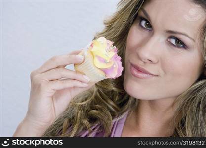 Portrait of a young woman eating a cupcake