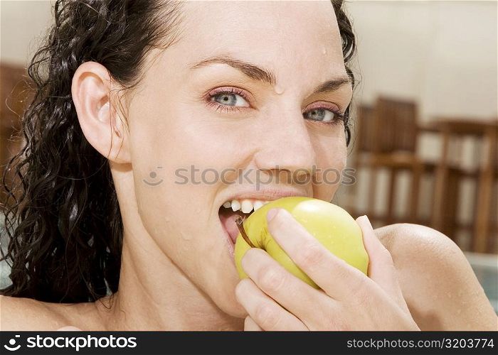 Portrait of a young woman eating a green apple