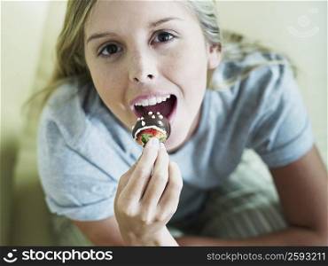 Portrait of a young woman eating a pastry