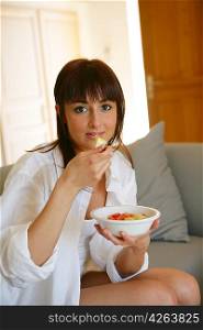 Portrait of a young woman eating a salad of fruits