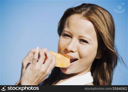 Portrait of a young woman eating a slice of melon