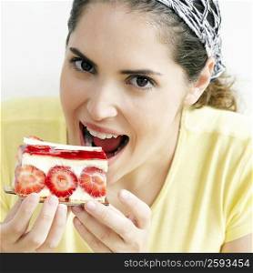 Portrait of a young woman eating a slice of strawberry cake