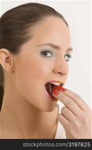 Portrait of a young woman eating a strawberry