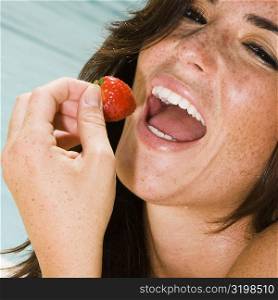 Portrait of a young woman eating a strawberry
