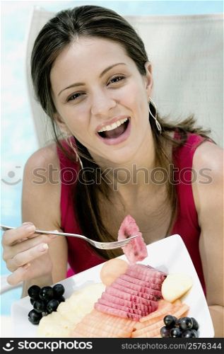 Portrait of a young woman eating fruit salad