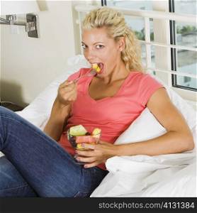 Portrait of a young woman eating fruit salad