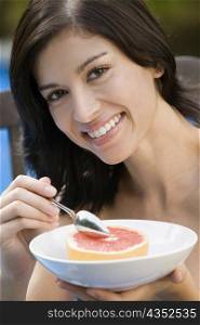 Portrait of a young woman eating grapefruit and smiling