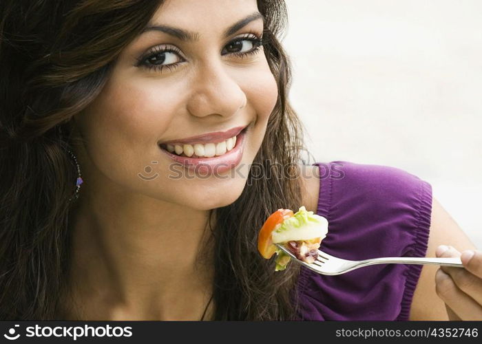 Portrait of a young woman eating salad and smiling