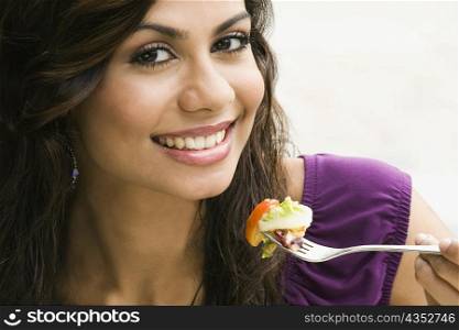 Portrait of a young woman eating salad and smiling