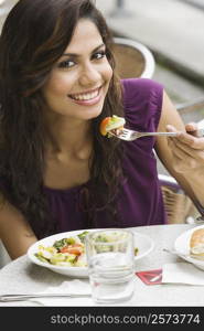 Portrait of a young woman eating salad at a sidewalk cafe