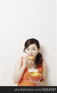 Portrait of a young woman eating slices of orange