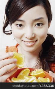 Portrait of a young woman eating slices of orange