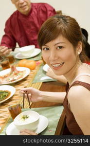 Portrait of a young woman eating with chopsticks