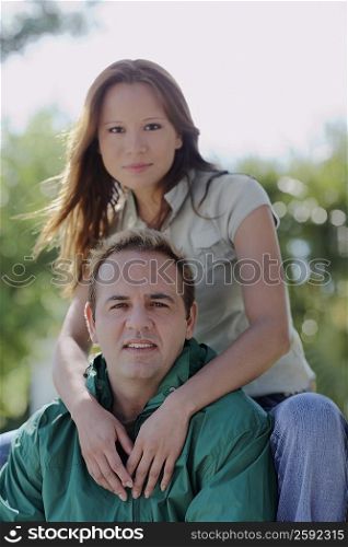 Portrait of a young woman embracing a mid adult man from behind
