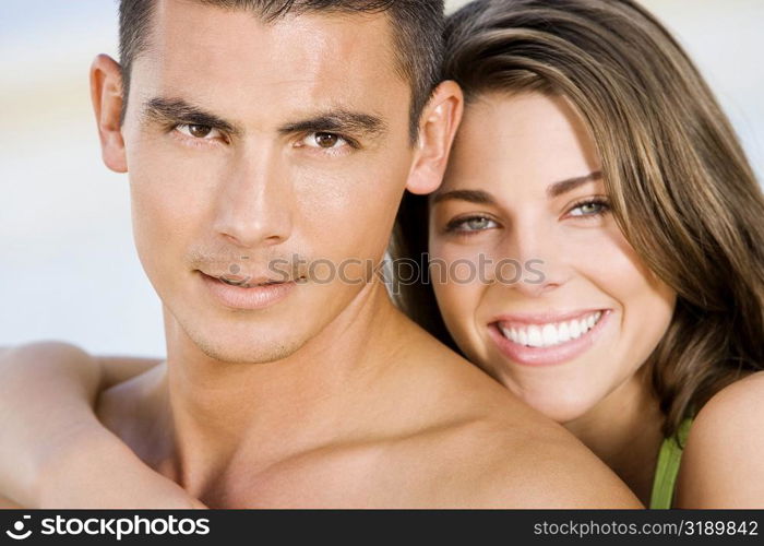 Portrait of a young woman embracing a young man from behind