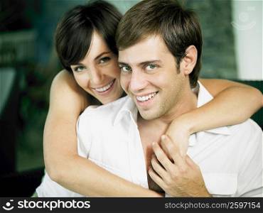 Portrait of a young woman embracing a young man from behind and smiling