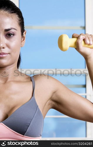 Portrait of a young woman exercising with a dumbbell