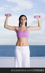 Portrait of a young woman exercising with dumbbells