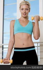 Portrait of a young woman exercising with dumbbells