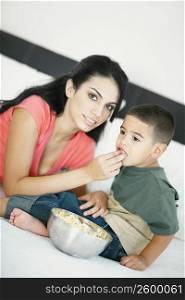 Portrait of a young woman feeding popcorn to her son
