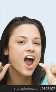 Portrait of a young woman flossing her teeth