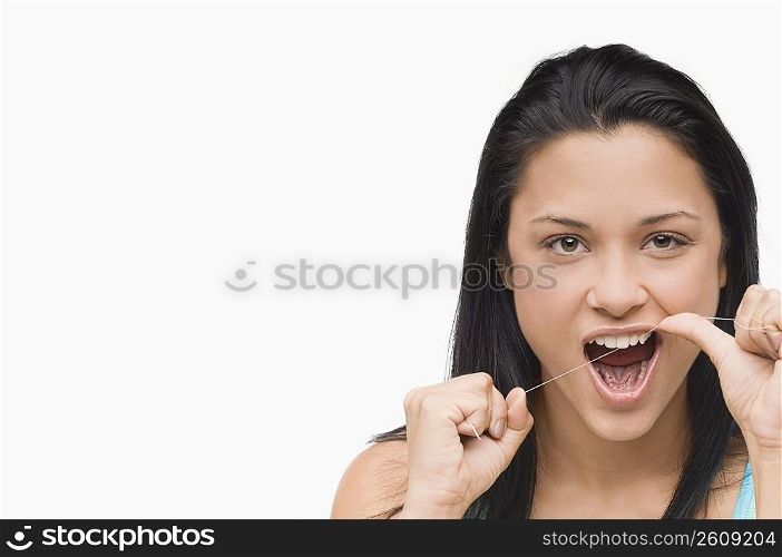 Portrait of a young woman flossing her teeth