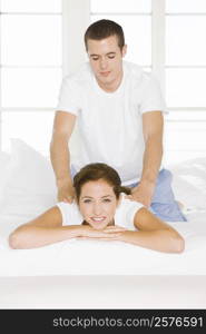 Portrait of a young woman getting a back massage from a young man