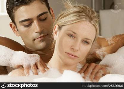 Portrait of a young woman getting a massage from a young man in a bubble bath