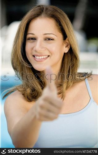 Portrait of a young woman giving thumbs up sign