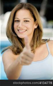 Portrait of a young woman giving thumbs up sign