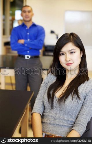 Portrait of a young woman grinning with a young man standing behind her