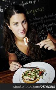 Portrait of a young woman having food in a restaurant