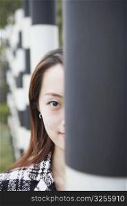 Portrait of a young woman hiding behind a column