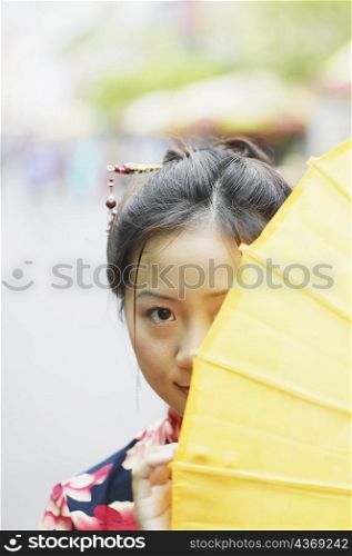 Portrait of a young woman hiding behind a parasol