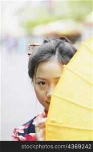 Portrait of a young woman hiding behind a parasol
