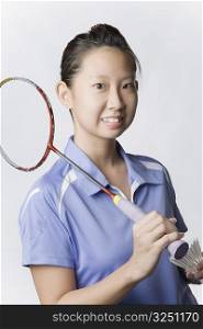 Portrait of a young woman holding a badminton racket and a shuttlecock