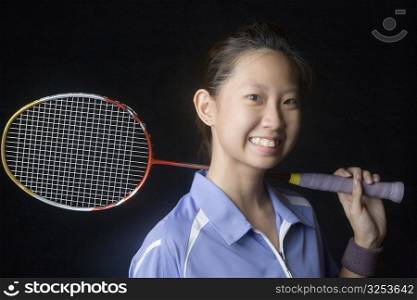Portrait of a young woman holding a badminton racket and smiling