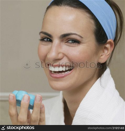 Portrait of a young woman holding a bar of soap