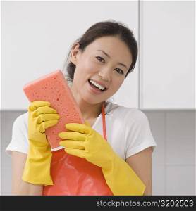 Portrait of a young woman holding a bath sponge and smiling
