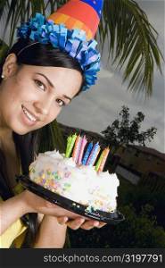 Portrait of a young woman holding a birthday cake and smiling