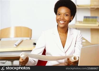 Portrait of a young woman holding a blueprint and smiling